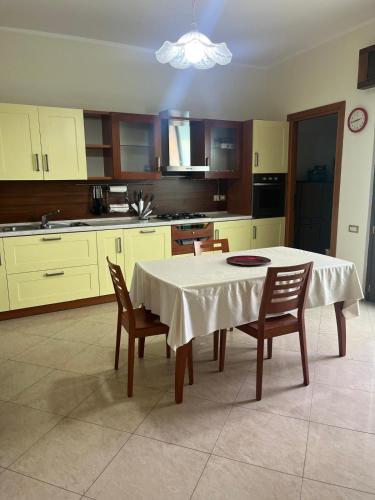 cocina con mesa con sillas y mantel blanco en Il Tramonto in centro, en Giba