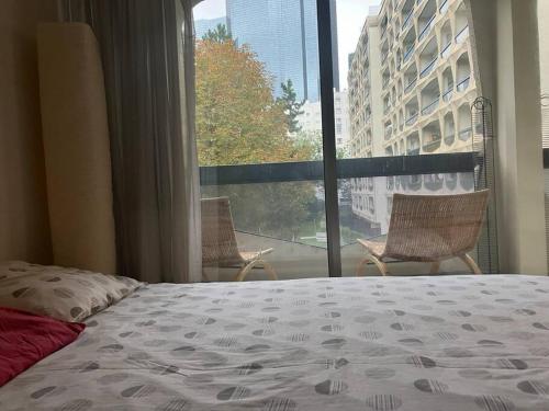 une chambre avec un lit et une grande fenêtre dans l'établissement Cozy flat in La Défense, à Courbevoie