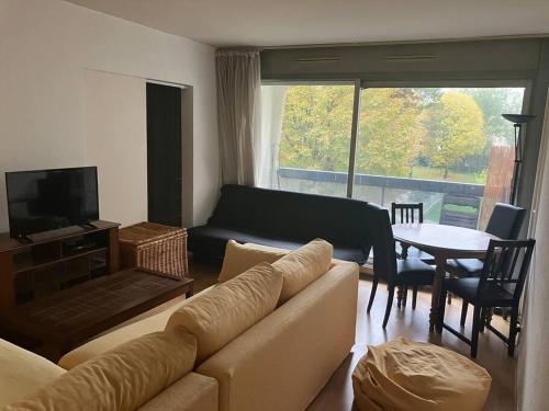 un salon avec un canapé, une télévision et une table dans l'établissement Cozy flat in La Défense, à Courbevoie