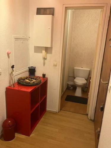 La salle de bains est pourvue d'une commode rouge et de toilettes. dans l'établissement Cozy flat in La Défense, à Courbevoie