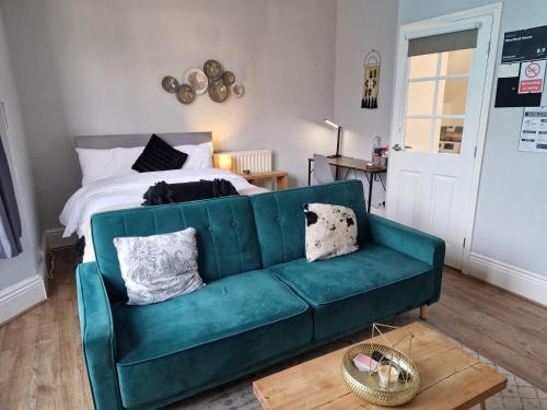 a living room with a green couch and a bed at West Beck House - Newcastle 2 in Newcastle upon Tyne