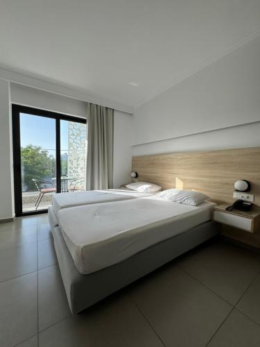 a bedroom with a large bed and a large window at Catherine Hotel in Kos Town
