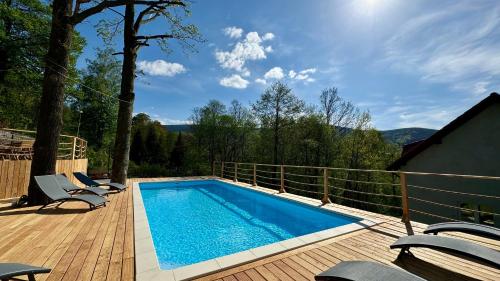 a swimming pool on a deck with chairs next to it at Apartamenty Larice - balia lub sauna sesja gratis ten weekend, morsowanie w basenie in Świeradów-Zdrój