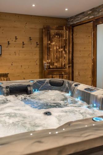 une baignoire jacuzzi dans une chambre avec un mur en bois dans l'établissement Chalet montagnard rénové avec jacuzzi 4****- 15 Personnes, à Saint-Sorlin-dʼArves