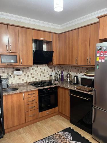 a kitchen with wooden cabinets and black appliances at ViLLA DALAMAN - AİRPORT in Dalaman