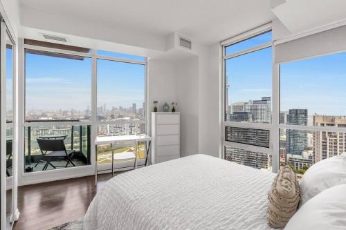 1 dormitorio con cama blanca y ventanas grandes en 2 BR with Amazing city views & Free parking en Toronto