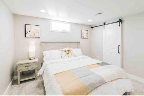 a white bedroom with a bed and a night stand at Beautiful luxury home freshly renovated with big yard, seating & grill pad in Cottage Grove
