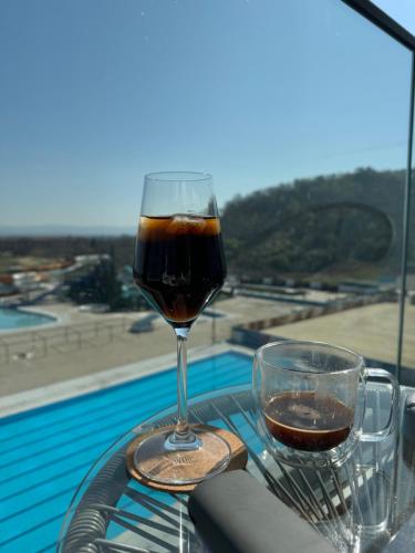 um copo de vinho sentado numa mesa perto de uma piscina em Bella Vista em Jagodina