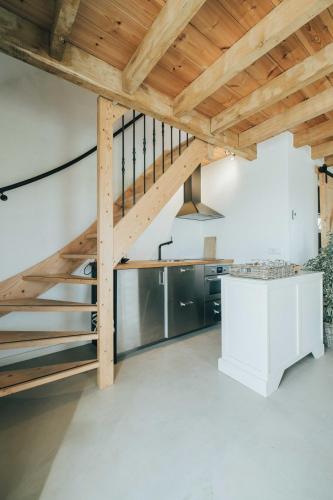 an attic kitchen with wooden ceilings and a staircase at Gastenverblijven boerderij Het Driespan in Middelburg