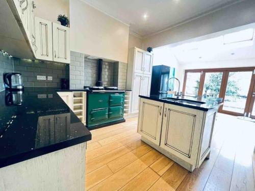 a large kitchen with black counter tops and green cabinets at Cricklewood Boutique Stay in London