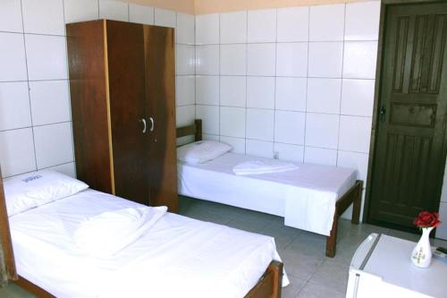 um quarto com duas camas e uma porta para um quarto em Hotel Paraty em Camaçari