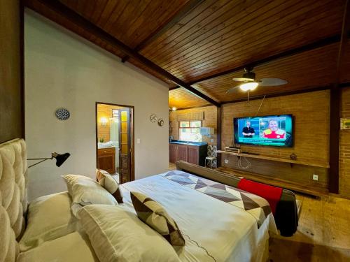 a bedroom with a bed and a flat screen tv at Pousada Chalés Jardim das Bromélias - Visconde de Mauá in Visconde De Maua