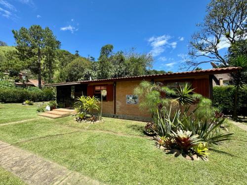 a small house with a yard with grass and plants at Pousada Chalés Jardim das Bromélias - Visconde de Mauá in Visconde De Maua