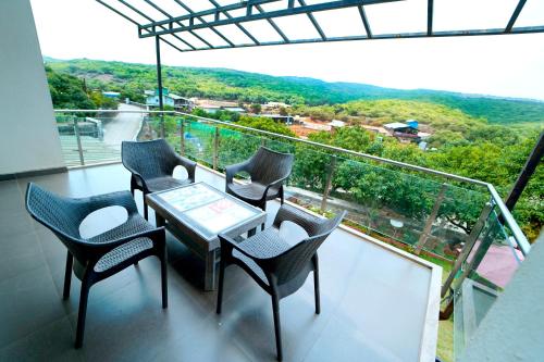 a balcony with a table and chairs and a view at Hotel Strawberry inn, Mahabaleshwar in Mahabaleshwar