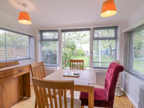 a dining room with a table and chairs and windows at The Annex in Colchester
