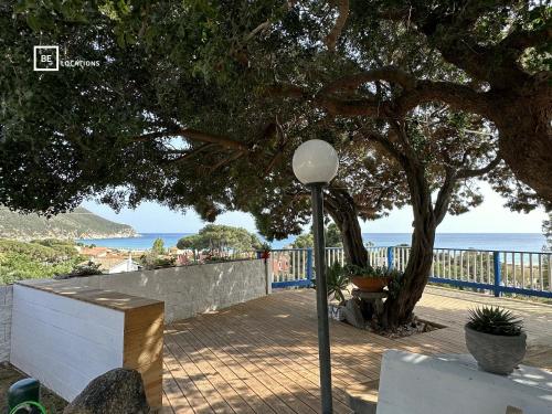 uma luz de rua ao lado de uma árvore e do oceano em Le Terrazze di Solanas - BeLocations em Solanas
