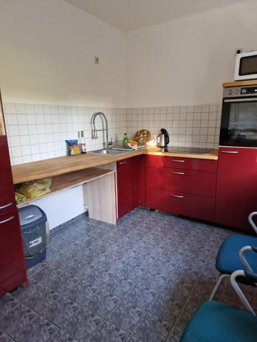 a kitchen with red cabinets and a sink at Fewo für Monteure 25km bis Berlin in Mittenwalde