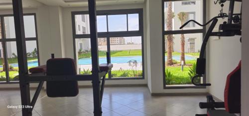 a gym with a view of a pool through windows at Cosy & Confort Studio près de l'aéroport in Nouaceur