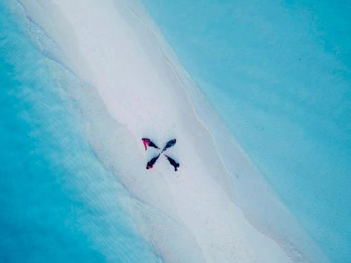 a bird flying over a white island in the ocean at Lazzlla beachside studio apartments in Hulhumale