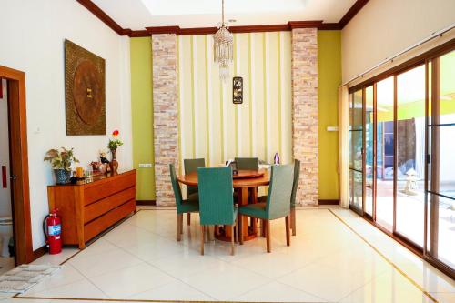 a dining room with a wooden table and green chairs at November T Pool Villa 2 in Jomtien Beach