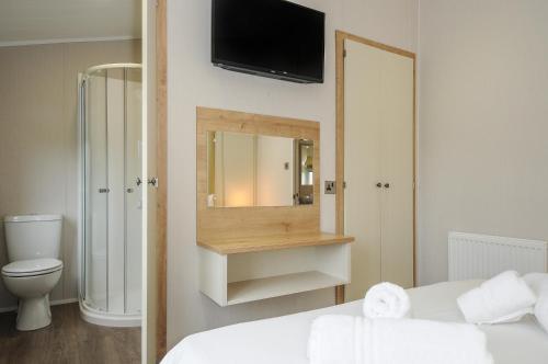 a bathroom with a bed and a mirror and a toilet at Lodge 74 at Riviera Bay Coastal Retreat in Brixham