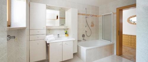 a white bathroom with a sink and a shower at Apartments Stroblhof in Ortisei
