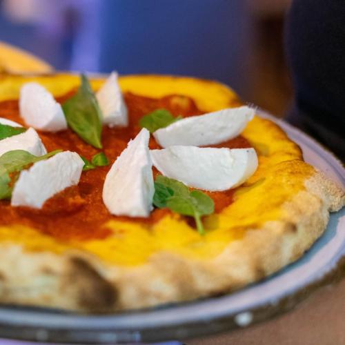 a pizza with cheese and toppings on a plate at Tola Dream Apartment in Sassari