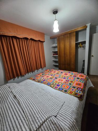 ein Schlafzimmer mit einem Bett mit einer bunten Bettdecke in der Unterkunft Pumahue Lodge in Temuco