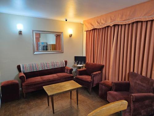 ein Wohnzimmer mit einem Sofa, Stühlen und einem Spiegel in der Unterkunft Pumahue Lodge in Temuco