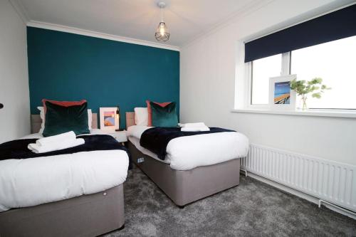 2 łóżka w pokoju z niebieską ścianą w obiekcie Beachfront Home with Ocean View w mieście Port Talbot
