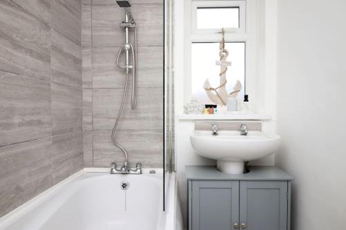 W łazience znajduje się wanna, umywalka i prysznic. w obiekcie Beachfront Home with Ocean View w mieście Port Talbot