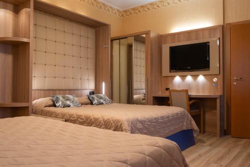 a hotel room with two beds and a flat screen tv at Hotel Vela D'oro ***S in Bardolino