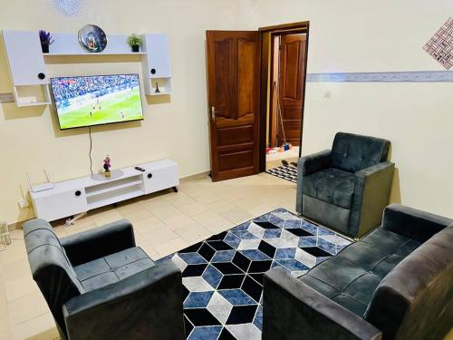 a living room with a couch and two chairs and a flat screen tv at Studio in Dakar