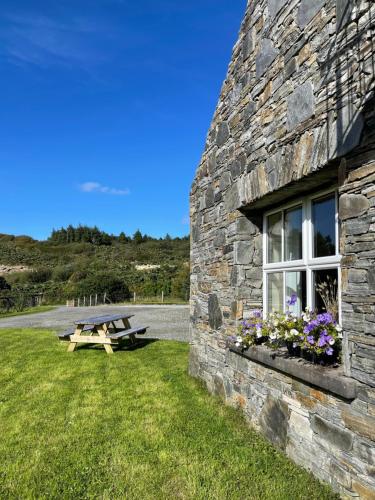 a picnic table next to a stone building with a window at Shanakeever Farm - 2 Bedroom Apartment in Clifden