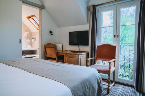 a bedroom with a bed and a desk and a television at Hotel Les Eleveurs in Halle