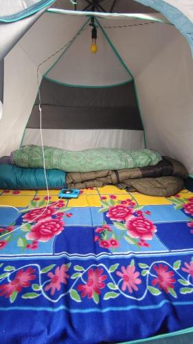 ein Bett in einem Zelt mit einer Decke darauf in der Unterkunft NamasteNomads X Musafirokibasti in Kedārnāth