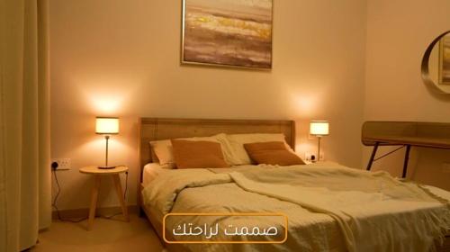 een slaapkamer met een bed met twee lampen op twee tafels bij خليج مسقط in Qantab