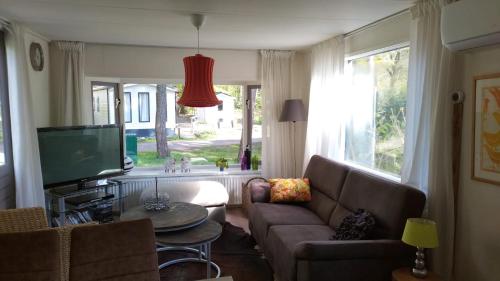 a living room with a couch and a tv at Wulft 47 Zonnig gezellig 6p chalet met zwembad in bosrijke omgeving op Familie Camping de Vossenburcht in IJhorst