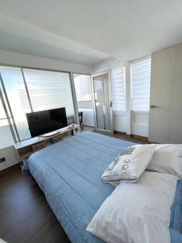 een slaapkamer met een bed, een televisie en ramen bij Loft de lujo,Vista panorámica in Manizales