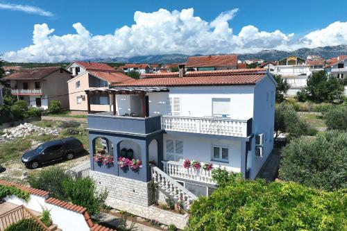 a white house with a balcony with flowers at Simaruna in Maslenica