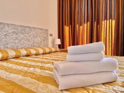 una pila de toallas sentadas encima de una cama en Bardolino Wein Apartments, en Bardolino