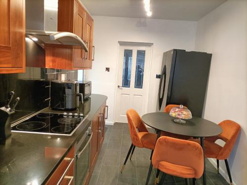 uma cozinha com uma mesa e uma cozinha com um frigorífico em Mill cottage em Carrickfergus