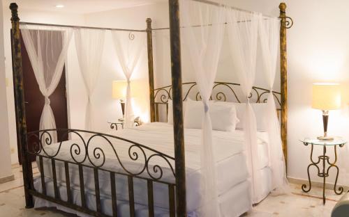 1 dormitorio con cama negra con dosel y sábanas blancas en Hotel Plaza Inn, en Los Mochis