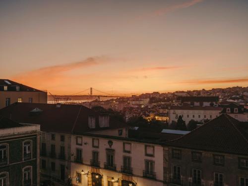 a city skyline at sunset with a bridge in the background at Patio do Tijolo in Lisbon