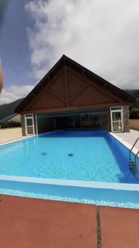 une grande piscine bleue avec un bâtiment dans l'établissement appart T 3 Bagnères-de-Luchon vue montagne - piscine mi juin, à Luchon