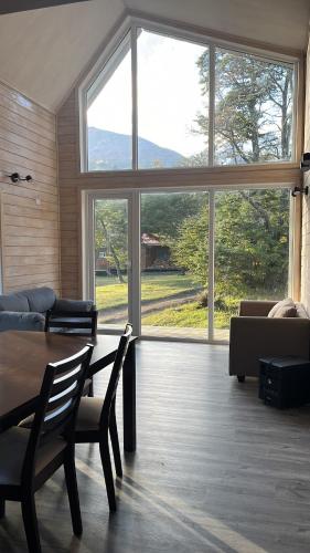 a living room with a table and a large window at QUELEN PATAGONIA in Villa Cerro Castillo