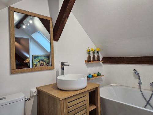 a bathroom with a sink and a tub and a mirror at Clair logis in Giverny