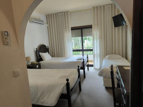 a hotel room with two beds and a window at Hotel Mira Serra in Celorico da Beira