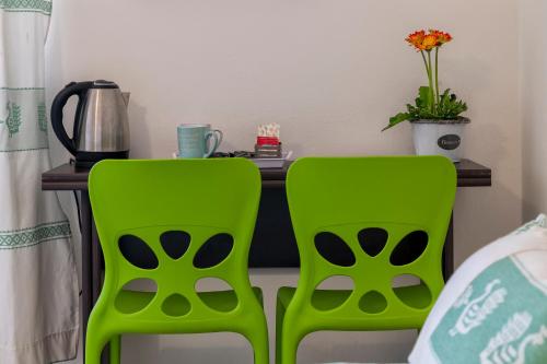 deux chaises vertes devant un bureau avec une table dans l'établissement HORIZON, à Alghero