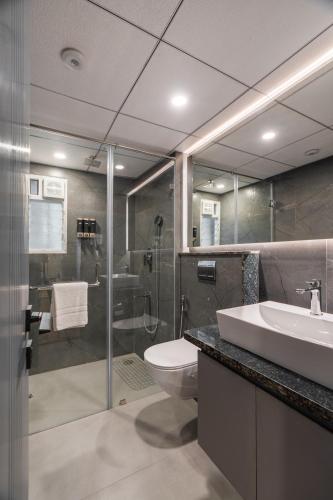 a bathroom with a toilet and a sink and a shower at Pelican Inn in Bangalore